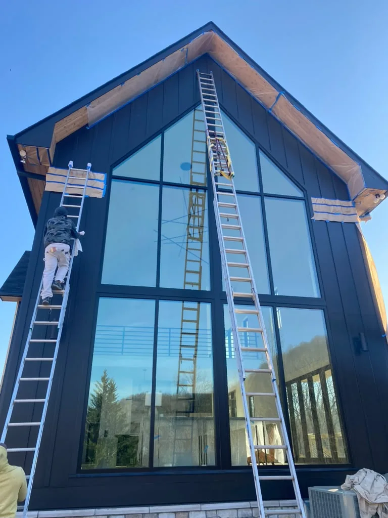 Exterior painting underway on a tall modern home